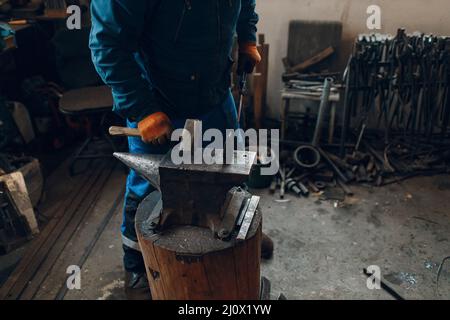 Forge forge et fait des détails en métal avec un marteau et une enclume à la forge Banque D'Images
