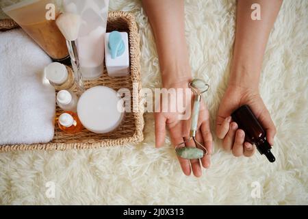 Les mains de la jeune femme montrant le rouleau de jade et la bouteille d'huile qu'elle utilise pour le visage masseuse Banque D'Images