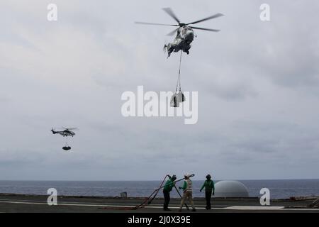 MER DES PHILIPPINES (19 mars 2022) des marins transportent des crochets de fret sur le pont de vol du porte-avions de la classe Nimitz USS Abraham Lincoln (CVN 72) lors d'un réapprovisionnement vertical en mer avec le navire de fret et de munitions du Commandement militaire de Sealift USNS Matthew Perry (T-AKE 9). Abraham Lincoln Strike Group est en cours de déploiement prévu dans la zone d'exploitation de la flotte américaine 7th afin d'améliorer l'interopérabilité par le biais d'alliances et de partenariats tout en servant de force d'intervention prête à l'emploi pour soutenir une région Indo-Pacifique libre et ouverte. (É.-U. Navy photo par Mass communication Specialist Seaman Apprentice Banque D'Images