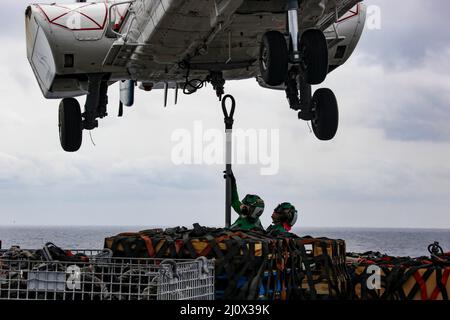 MER DES PHILIPPINES (19 mars 2022) Spécialiste en logistique le marin Cameron Mudgett, à gauche, de Carlsbad (Californie), et Spécialiste en logistique 3rd classe Paola Barragan, de McAllen (Texas), placez un crochet de fret sur un Super Puma AS332 sur le pont de vol du porte-avions de la classe Nimitz USS Abraham Lincoln (CVN 72) Au cours d'un réapprovisionnement vertical en mer avec le navire de fret et de munitions du Commandement du Seallift militaire USNS Matthew Perry (T-AKE 9). Abraham Lincoln Strike Group est en cours de déploiement prévu dans la zone d'exploitation de la flotte américaine 7th afin d'améliorer l'interopérabilité par le biais d'alliances et de partenariats Banque D'Images