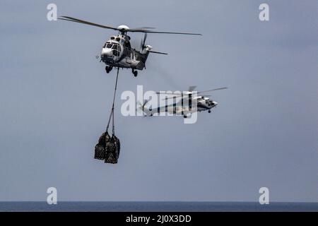 MER DES PHILIPPINES (19 mars 2022) un Super Puma AS332 transporte du fret au porte-avions de la classe Nimitz USS Abraham Lincoln (CVN 72) du navire de fret et de munitions du Commandement militaire de Sealift USNS Matthew Perry (T-AKE 9) lors d'un réapprovisionnement vertical en mer. Abraham Lincoln Strike Group est en cours de déploiement prévu dans la zone d'exploitation de la flotte américaine 7th afin d'améliorer l'interopérabilité par le biais d'alliances et de partenariats tout en servant de force d'intervention prête à l'emploi pour soutenir une région Indo-Pacifique libre et ouverte. (É.-U. Photo de la marine par la spécialiste en communication de masse apprenti Julia Brock Banque D'Images