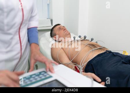 Équipement médical pour électrocardiogramme. Médecins effectuant un test ECG sur un patient masculin. Diagnostic de maladie cardiaque crise cardiaque, tachycarne Banque D'Images