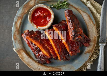 Viande de keto, côtes de porc épicées au barbecue. Recette de cuisson lente. Viande de porc rôtie marinée avec sauce rouge. Banque D'Images