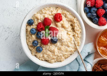 Porridge de flocons d'avoine avec myrtille, framboises, confiture, vue de dessus, gros plan. Petit déjeuner avec baies Banque D'Images