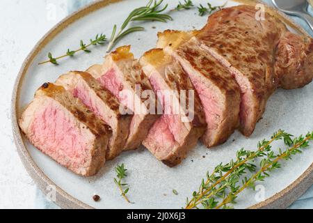 Steak de bœuf cétogène, striploine sur plaque grise sur fond blanc Banque D'Images