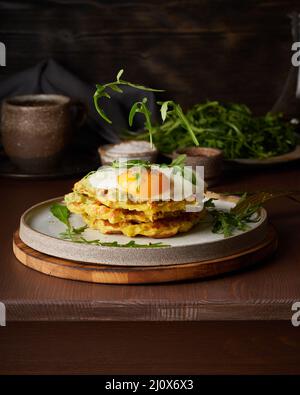 Gaufres belges de pommes de terre faites maison avec œuf frit, sauce à l'avocat, roquette volante, mozzarella. Banque D'Images