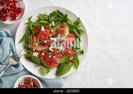 Vue de dessus fruits salade d'agrumes avec noix, laitue verte. Épinards à l'orange, au pamplemousse, aux pacanes Banque D'Images