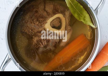 Bouillon de viande de bœuf, l'ossobuco sur l'os, soupe riche dans une casserole, longue cuisson lente. Banque D'Images