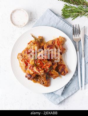 Ailes de poulet au barbecue. Chiken cuit au four sur une assiette de sauce rouge. Plats asiatiques chauds. Vue de dessus, verticale Banque D'Images