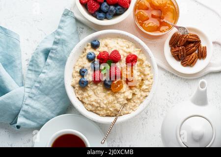 Porridge de flocons d'avoine avec bleuets, framboises, confiture et noix, vue de dessus. Petit déjeuner avec baies Banque D'Images