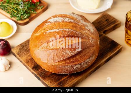 Pain complet de pain de blé blanc fraîchement cuit sur bois planche sur la table de cuisine de la maison Banque D'Images