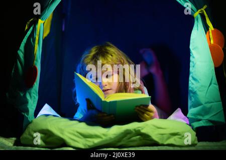 Livres de lecture pour enfants. Petit garçon dans les enfants tentat maison regardant des images dans le livre d'histoire. Enfant faisant ses devoirs à l'école primaire. Étude des enfants. Banque D'Images