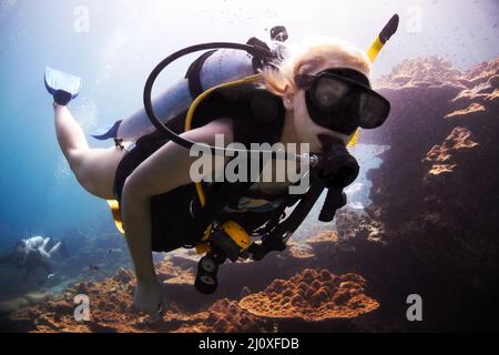 Aventurier de l'océan. La plongée sous-marine féminine passe près d'un récif de corail. Banque D'Images