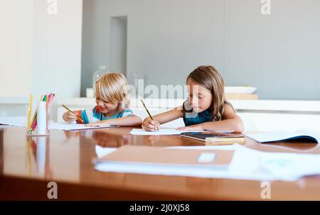 L'école est fraîche et ils le savent déjà. Photo de deux adorables jeunes enfants faisant leurs devoirs ensemble à la maison. Banque D'Images