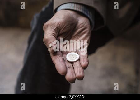 Homme sans abri tenant la pièce de sa main. Concept de photo de haute qualité Banque D'Images