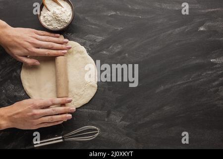 Les mains roulent la pâte à pain avec le fouet. Photo de haute qualité Banque D'Images