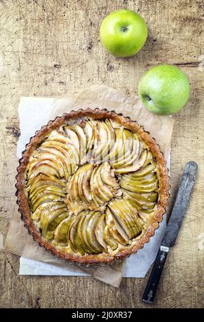 Gâteau aux pommes français traditionnel offert comme vue de dessus sur un papier de fond sur un panneau en bois Banque D'Images