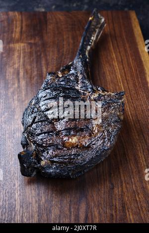 Le steak de Tomahawk de Chianina, vieux et sec, au barbecue moderne, sert de gros plan sur un panneau en bois Banque D'Images