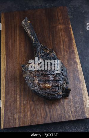 Le steak de Tomahawk de Chianina, vieux et sec, au barbecue moderne, sert de gros plan sur un panneau en bois Banque D'Images