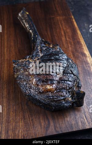 Le steak de Tomahawk de Chianina, vieux et sec, au barbecue moderne, sert de gros plan sur un panneau en bois Banque D'Images