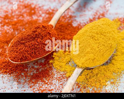 Deux boules d'épices de paprika en poudre et de curcuma, curry, poudre éparpillées sur la table en bois bleu clair Banque D'Images