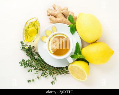 Les façons populaires de traiter les rhumes - tasse de thé et une tranche de citron, gingembre, menthe, miel, herbes, citrons entiers et moitié sur un backgro blanc Banque D'Images