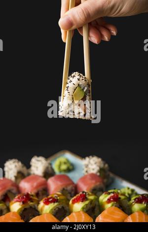 Personne tenant des sushis avec des baguettes. Photo de haute qualité Banque D'Images