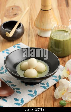 Matcha Tangyuan (Tang Yuan) avec soupe au thé vert doux dans un bol en céramique noire sur une table en bois pour le Festival Food Winter Solstice Banque D'Images