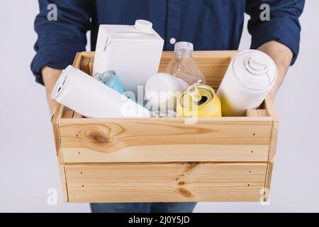 Boîte en bois de la main de l'homme, bouteilles pleines, boîtes de conserve. Photo de haute qualité Banque D'Images