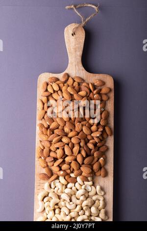 Directement au-dessus de la dose d'amandes et de noix de cajou sur une planche de service en bois sur fond gris Banque D'Images