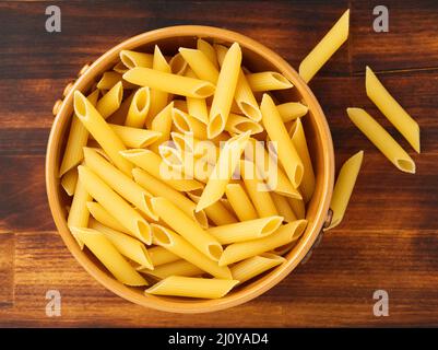 Pâtes Tortiglioni dans un bol brun sur une table brune en bois foncé. Vue de dessus. Banque D'Images