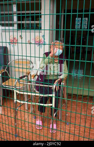 Hong Kong, Chine. 21st mars 2022. Une femme âgée est assise à l'extérieur de la maison de retraite où elle vit à Hong Kong. Plus de la moitié des personnes décédées de Covid à Hong Kong résidaient chez elles pour personnes âgées. Ces foyers de soins sont occupés par près de 60 000 personnes et environ 14 700 d'entre elles ont été infectées depuis le début de la cinquième vague. Crédit : SOPA Images Limited/Alamy Live News Banque D'Images