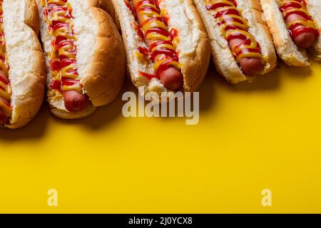 Vue en grand angle des sauces sur hot dogs disposées côte à côte sur fond jaune Banque D'Images