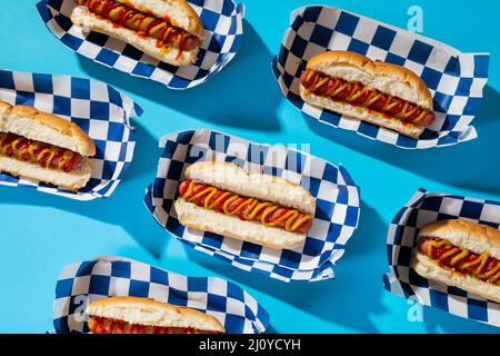 Vue en grand angle des hot dogs dans les récipients disposés sur fond bleu Banque D'Images