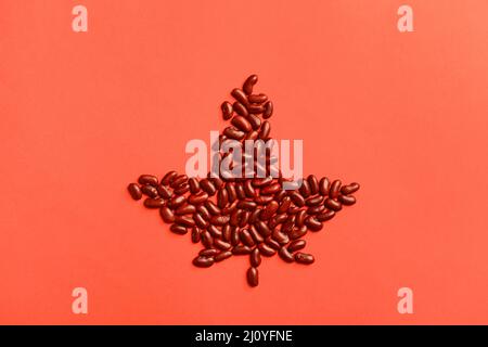 Feuille d'érable à base de haricots sur fond rouge. Concept de drapeau canadien Banque D'Images