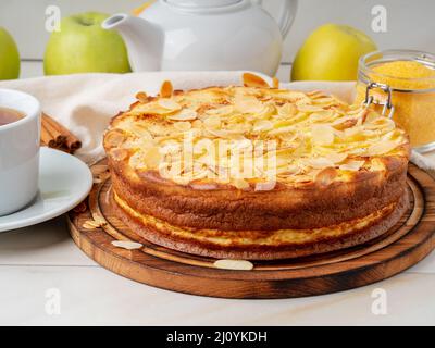 Cheesecake, tarte aux pommes, dessert au curd avec polenta, pommes, flocons d'amandes et cannelle sur table de cuisine en marbre blanc, vue latérale Banque D'Images