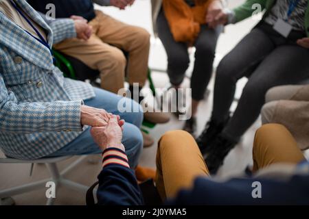 Groupe d'aînés tenant les mains et priant pour l'Ukraine ensemble dans le centre communautaire de l'église, gros plan. Banque D'Images