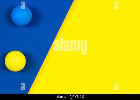 Résumé minimum de jouets pour enfants fond. Petites balles de jouet jaunes et bleues sur fond géométrique jaune et bleu. Vue de dessus Banque D'Images