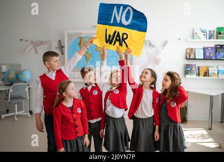 De petits écoliers qui hochaient et qui montraient le drapeau ukrainien dans la salle de classe, pas de concept de guerre. Banque D'Images