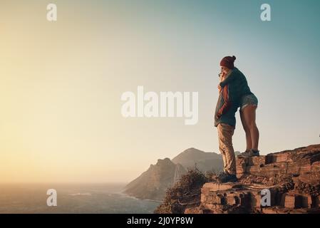 Cette vue est incroyable. Photo en longueur d'un jeune couple affectueux prenant la vue depuis un sommet de montagne. Banque D'Images