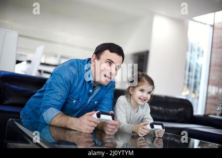 Jeune homme souriant jouant au jeu vidéo avec petite fille dans le salon moderne regardant à l'écran pendant le jeu. Passer du temps en famille ensemble Banque D'Images