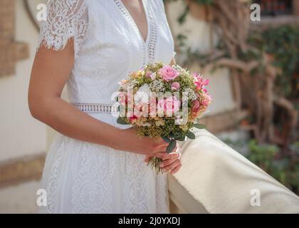 Beau bouquet de mariage rose de fleurs séchées conservées par la femme en robe d'été de mariée blanche Banque D'Images