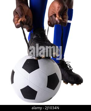 Bas de section de l'africain américain joueur de football nouant le cordonnet sur le ballon sur fond blanc Banque D'Images