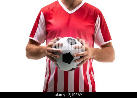 Section médiane d'un jeune homme caucasien tenant le ballon de football debout sur fond blanc Banque D'Images