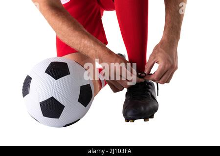 Une faible section de jeunes athlètes de race blanche nouant la chaussure par le ballon de football sur fond blanc Banque D'Images