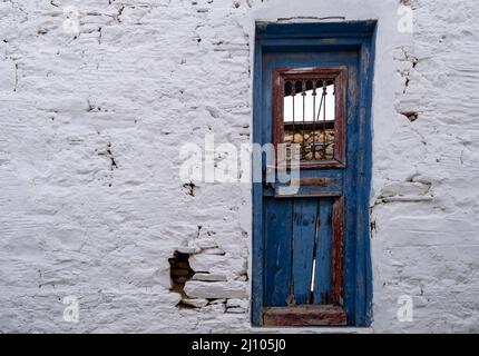 Île grecque, Cyclades. Bleu bois fermé porte ancienne cassée, abîmée, grès blanchi à la chaux endommagé. Grèce destination vacances d'été. Copier l'espace Banque D'Images