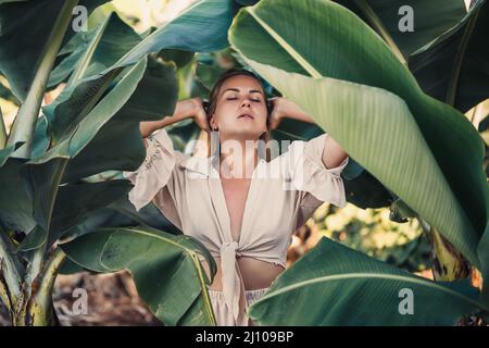 Belle femme dans la jungle. Un centre de villégiature ou un hôtel avec des arbres et des plantes tropicaux. Femme avec près de la feuille de banane. Fille en vacances dans la forêt tropicale Banque D'Images