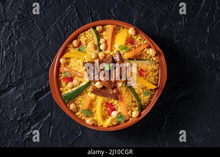 Couscous de viande et de légumes, cuisine marocaine traditionnelle, tiré du dessus, avec pois chiches sur fond noir Banque D'Images