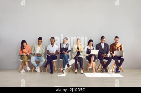 Femme en rangée avec des gens qui sont venus pour l'entrevue et sont occupés à lire des CV ou surfer sur Internet. Banque D'Images