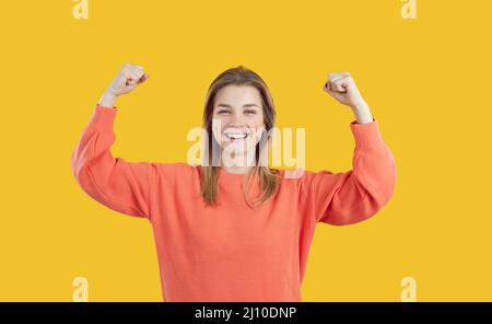 Une dame heureuse et confiante souriant et en montrant ses bras illustrant le concept de puissance de fille Banque D'Images